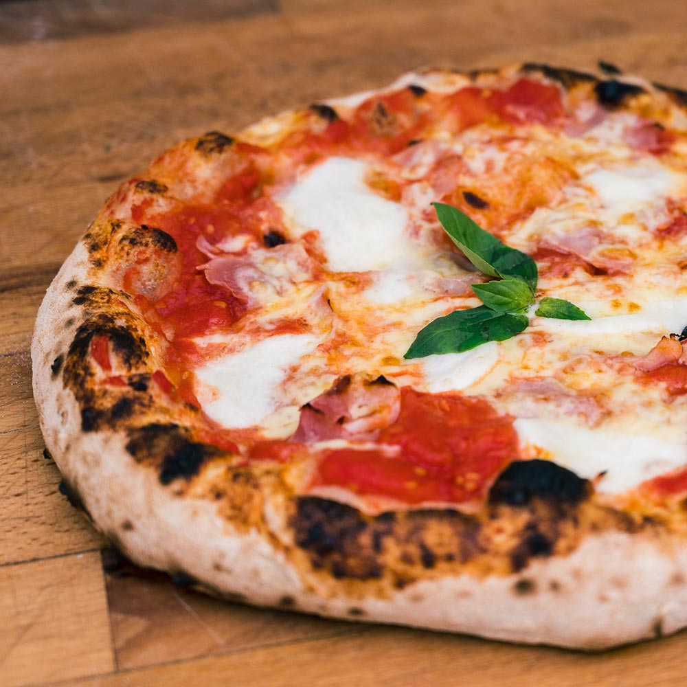Wood oven fired margherita pizza on a wooden board.