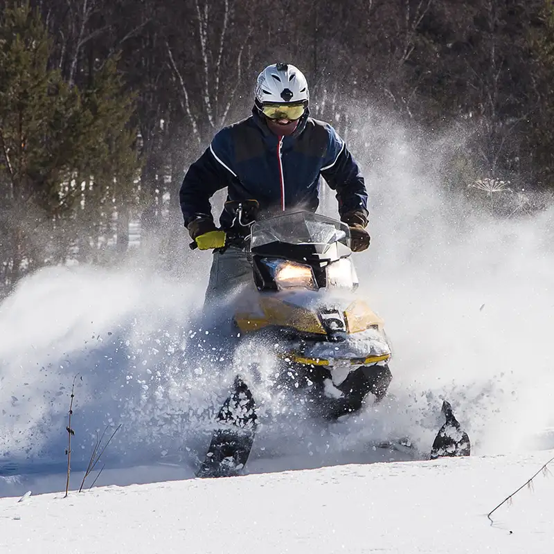 Person riding a snowmobile in the forest. Photo credit: Magnific by 02irina